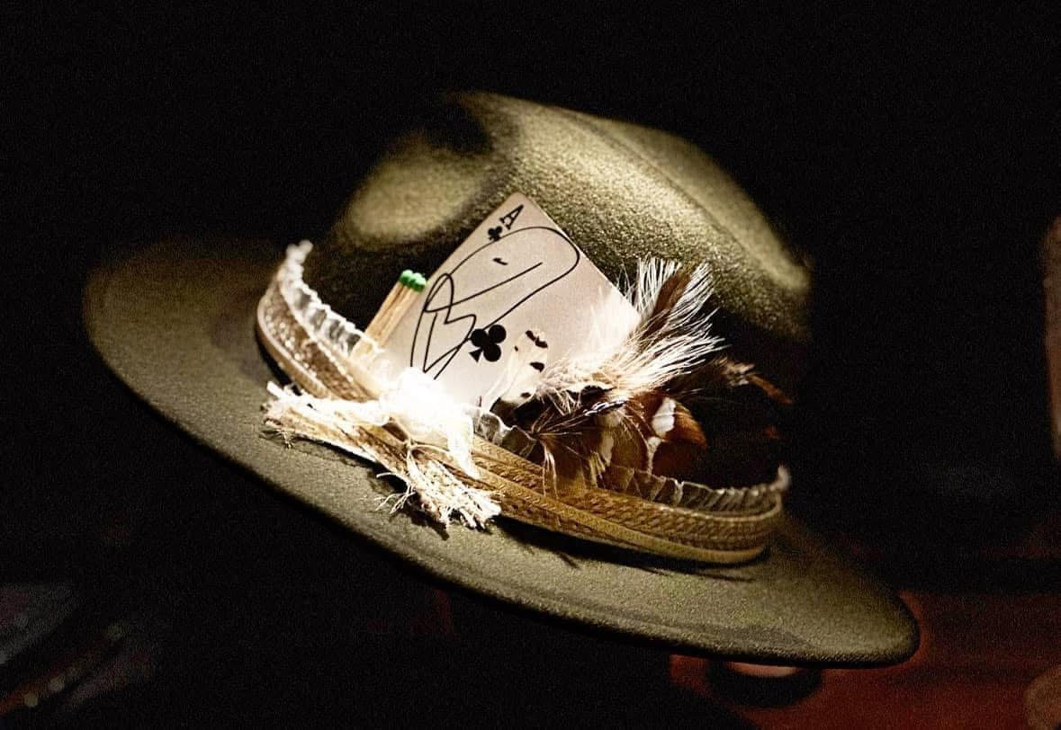 Dark, moody editorial photograph of a handcrafted western hat